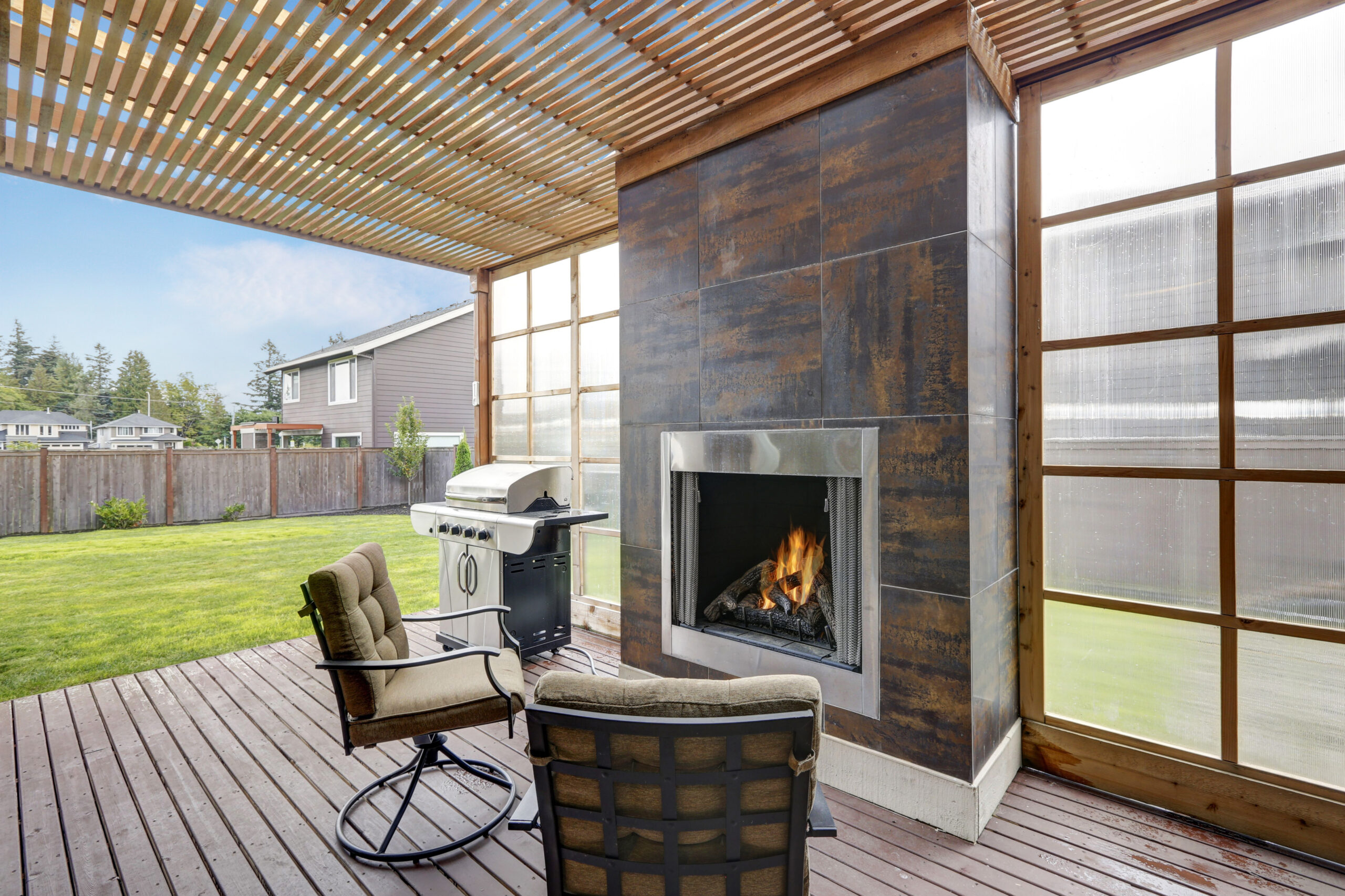 outdoor fireplace and grill beneath a pergola