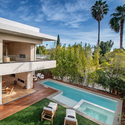 Luxurious pool surrounded by a beautiful wood deck and palm trees