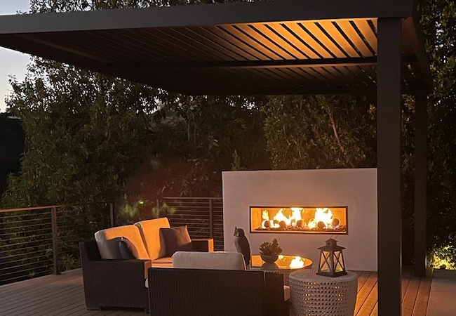 Sophisticated pergola by MG Construction & Decks over an outdoor fireplace and plush patio furniture