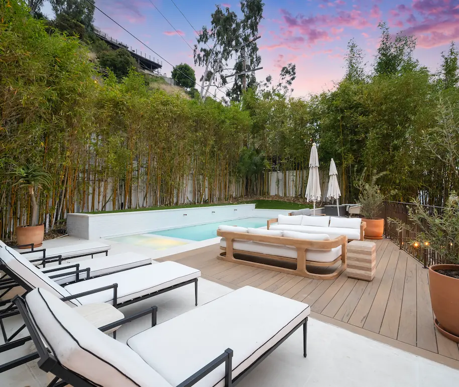 A deck with sun loungers, enclosed by a wall with greenery. Depicts a vertical garden